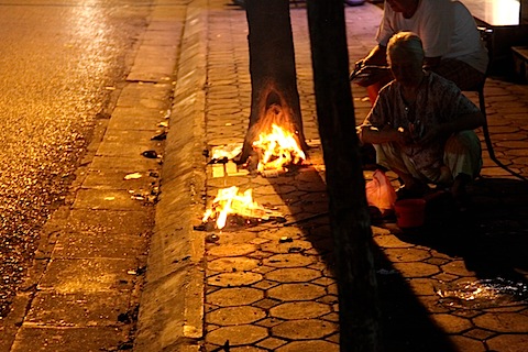 Woman burning offerings at night