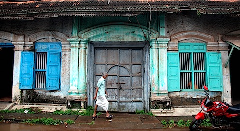 Man walking past decaying building